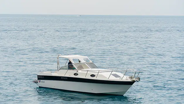 Sleek Wellcraft 3300 express cruiser anchored in front of the colorful houses of Positano Italy