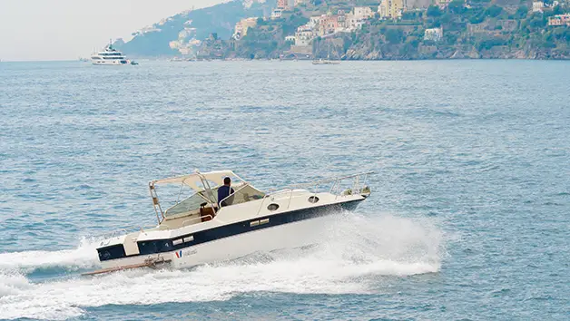 Premium Wellcraft 3300 motorboat moored in a hidden crystal-clear cove near Amalfi for a private swimming trip